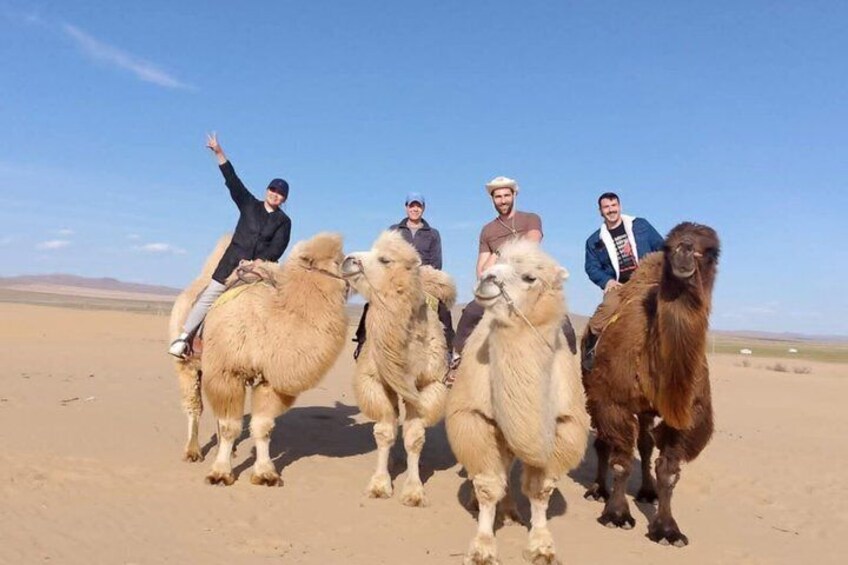 Een groep mensen die op kamelen door een woestijnlandschap rijdt. 2