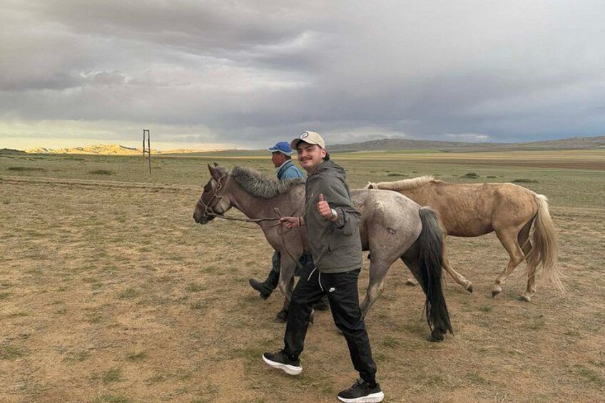 Dos personas guiando dos caballos en un campo cubierto de hierba bajo un cielo nublado. 3