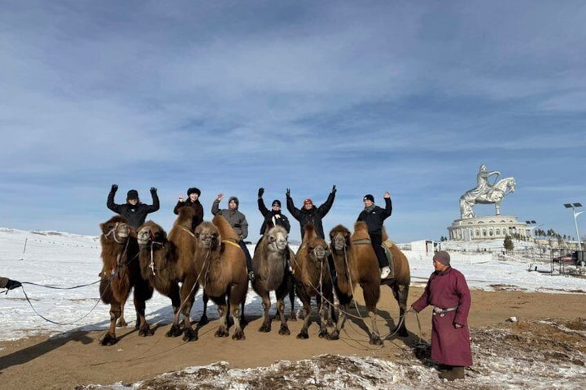 Eine Gruppe Reiter in einer verschneiten Landschaft, im Hintergrund eine Statue. 1