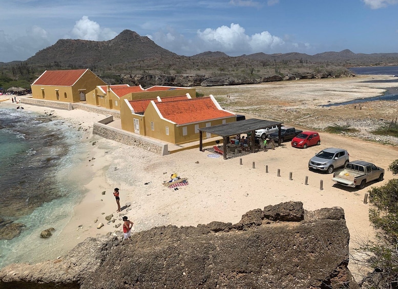 A coastal area with buildings, a beach, and a mountainous backdrop. 2