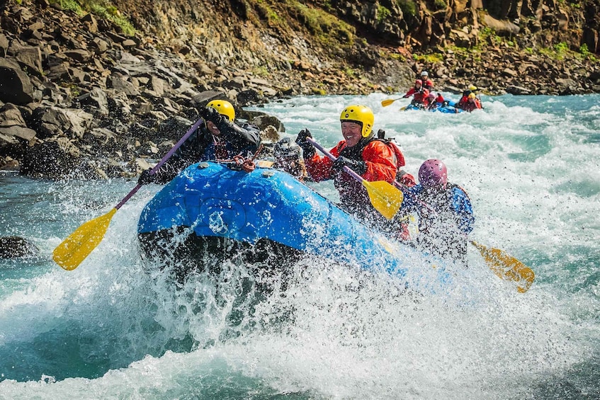 A group of people kayaking on a river with rocky banks. 2