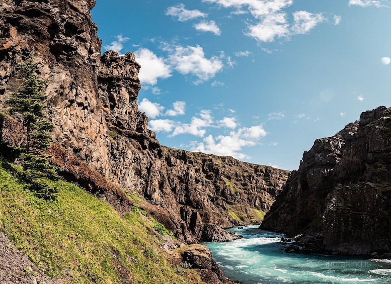 A river flowing through a rocky canyon with steep cliffs and sparse vegetation. 3