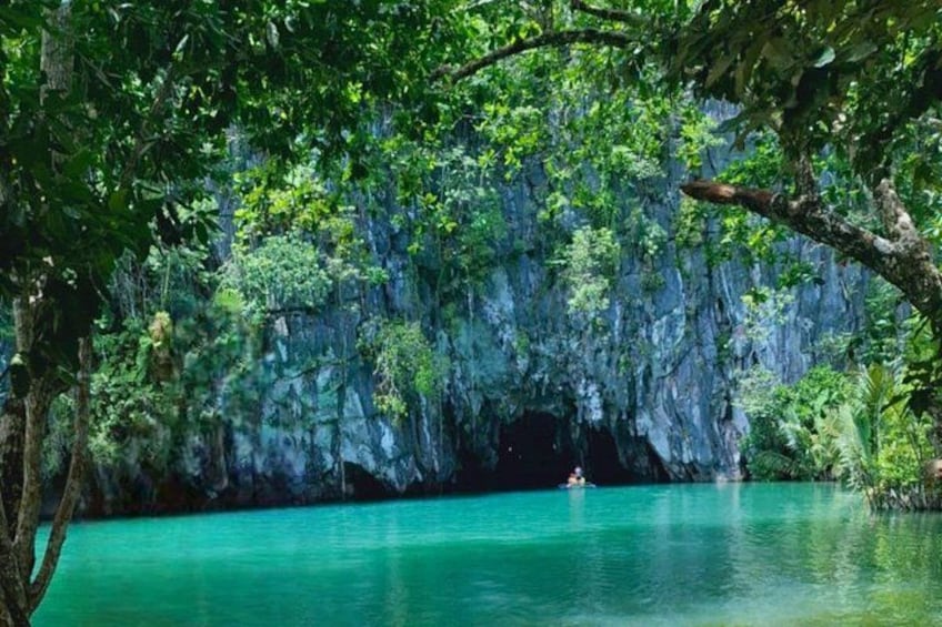 Une étendue d’eau turquoise, entourée d’une végétation luxuriante, et une structure ressemblant à une grotte. 1