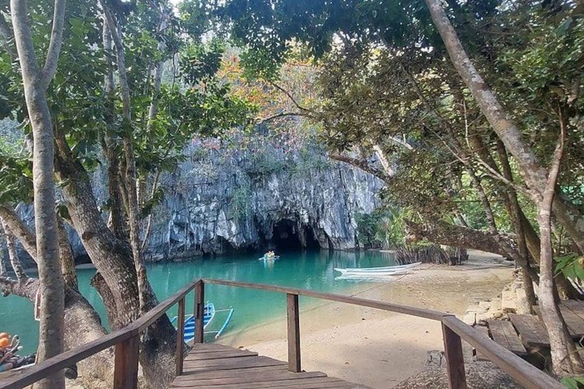Un escalier en bois mène à une plage, avec une grotte en arrière-plan. 2