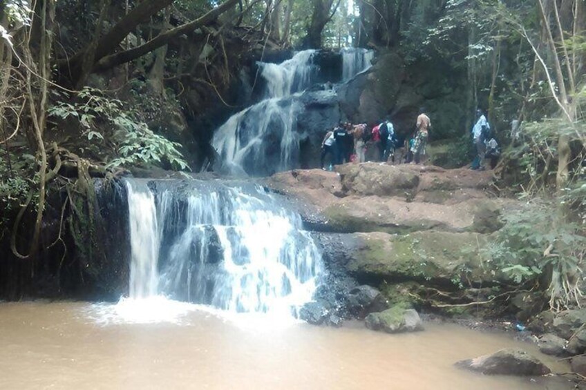 Une cascade avec des personnes debout sur un rebord rocheux. 1