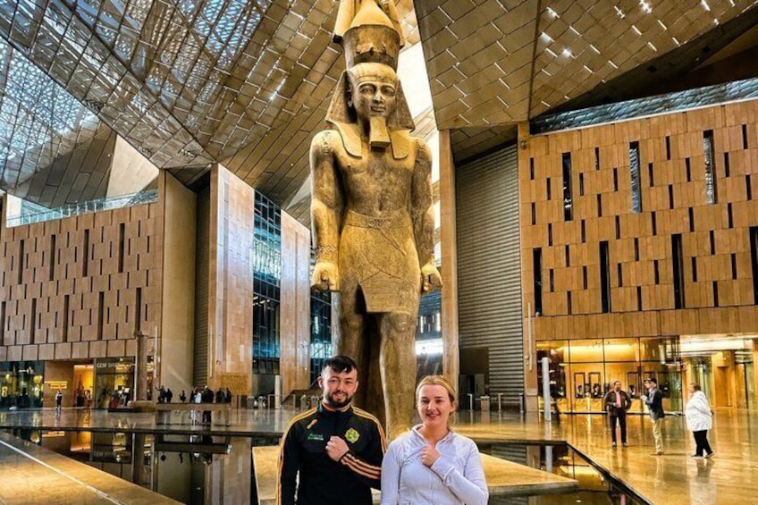 En stor, forntida egyptisk staty i en modern byggnad med ett glastak och träpanel. 5