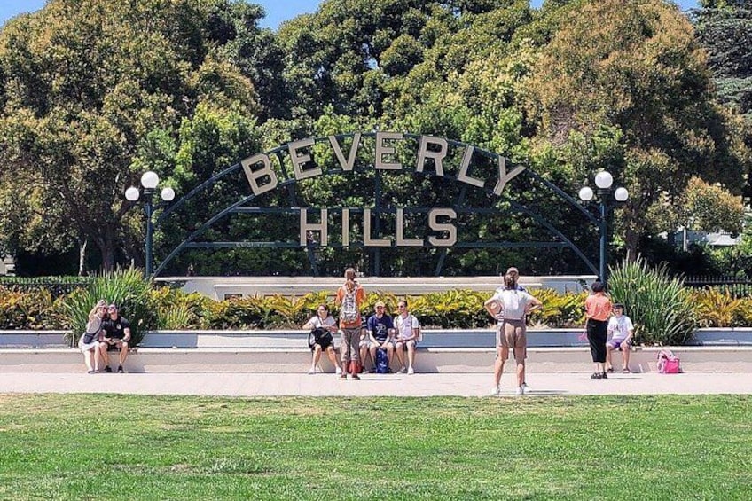 Un panneau indiquant « BEVERLY HILLS », avec des personnes assises et debout devant. 4