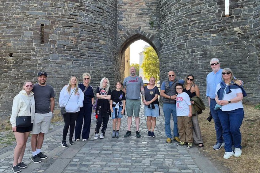 Een groep mensen staat voor een stenen bogenpoort. 5