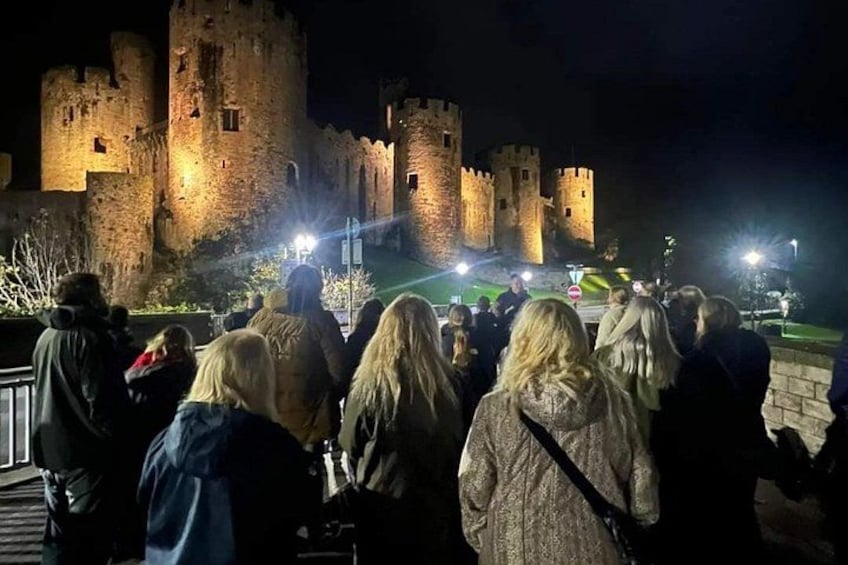 Een groep mensen verzameld voor een kasteel in de nacht. 1