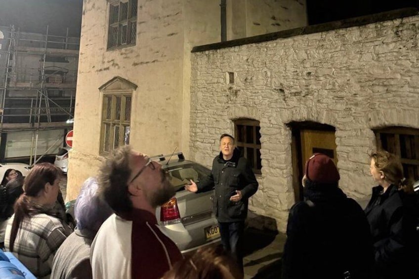A group of people standing outside a stone building at night. 3