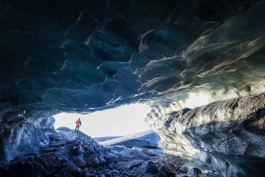 Une personne se tient dans une grotte de glace, avec une vue sur un paysage lointain. 5