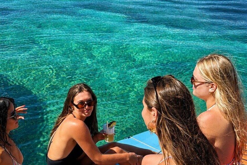 A group of people sitting by a pool with clear blue water. 5