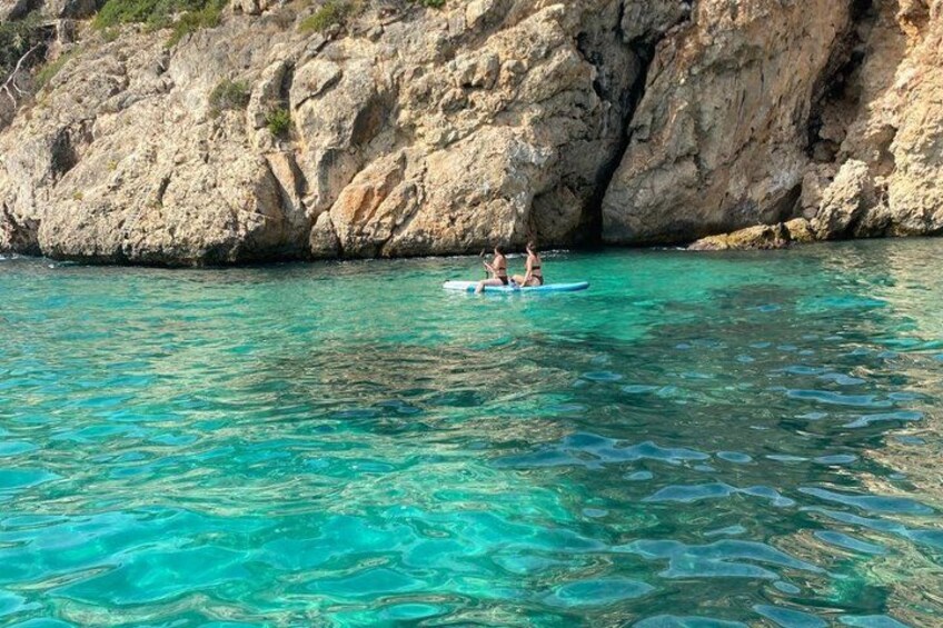 A clear turquoise sea with two people on a small boat. 2