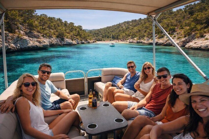 A group of people on a boat with a clear blue sea and rocky coastline in the background. 1