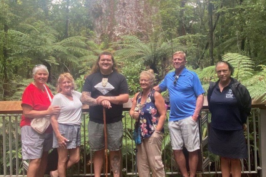 A group of people standing on a wooden deck surrounded by lush greenery. 2