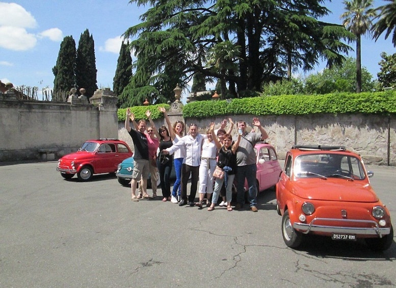 A group of people standing in a parking lot with vintage cars. 4