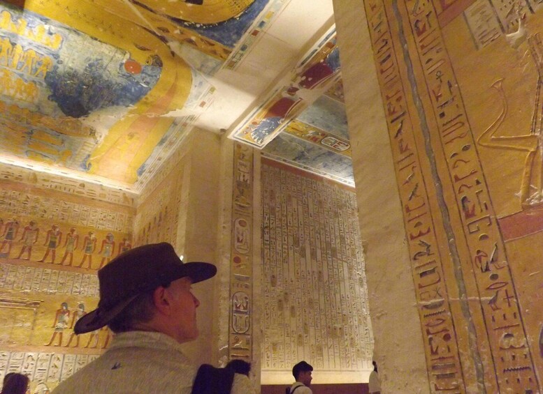 A person examining hieroglyphics on a wall in a museum. 5
