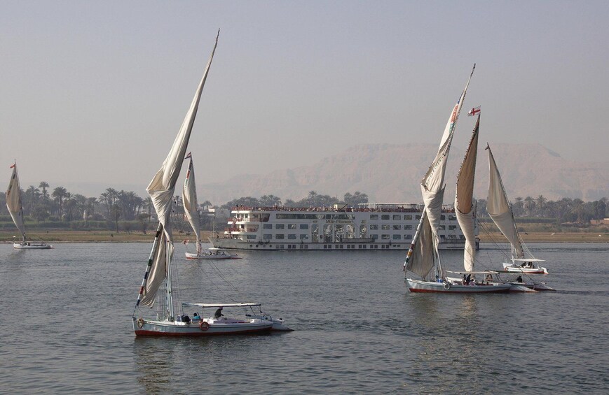 Sailboats on a river with a large building in the background. 4