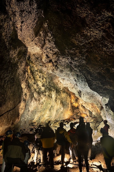 A group of people exploring a cave with illuminated walls. 3