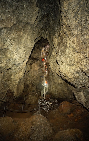 A cave with a metal staircase descending into a lower chamber. 5