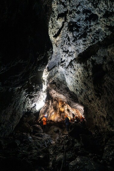 A cave interior with rough rock surfaces and a small opening at the bottom. 4