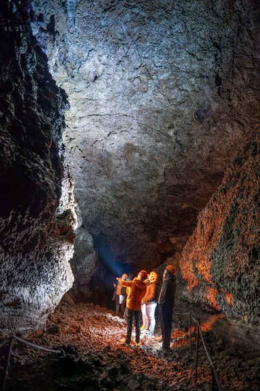 A group of people exploring a cave with rocky walls and a narrow passage. 3