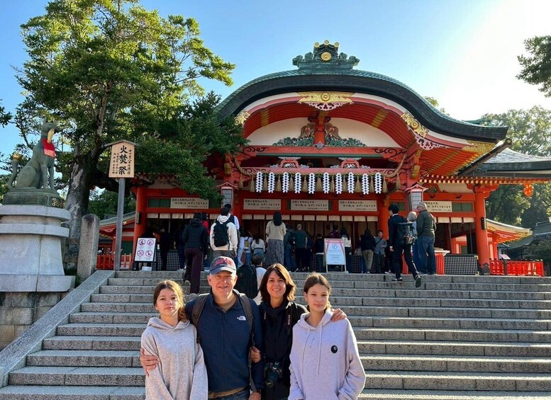 A traditional Japanese temple with a curved roof, a stone statue, and visitors ascending the steps. 4