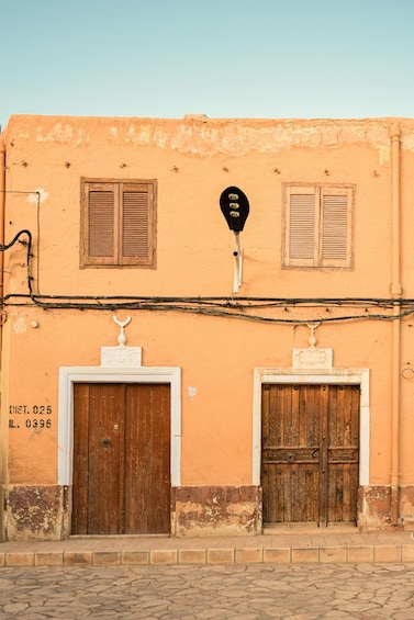 A building with two wooden doors, a street lamp, and a cobblestone street. 5