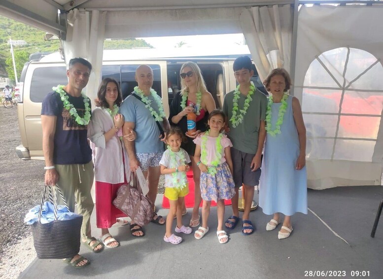 A group of people standing in front of a vehicle, some wearing leis. 4