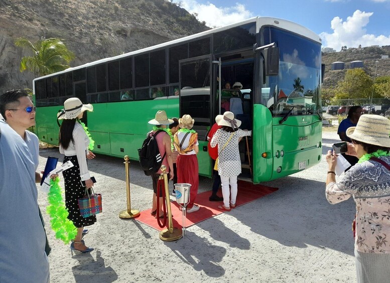 A group of people boarding a green bus with a red carpet on the ground. 2