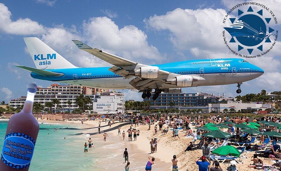 A KLM Asia airplane taking off over a crowded beach with umbrellas and people. 1