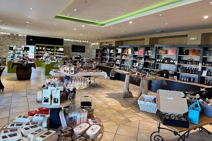 A retail store with shelves stocked with various products, a display table with items, and a counter with a menu. 2