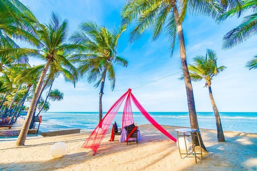 A beach with a red canopy tent, palm trees, and a sandy shore. 3