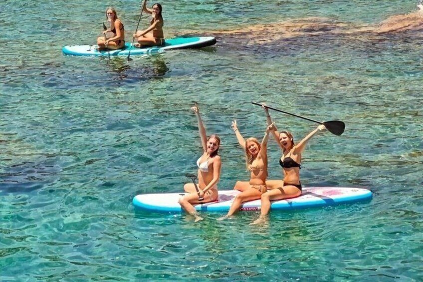 Tre personer på paddleboards i klart vand. 1