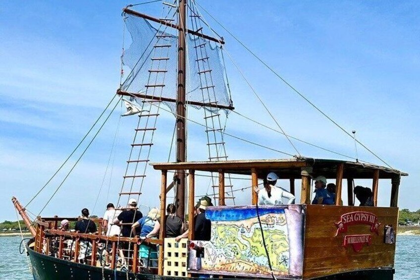Un barco de vela con pasajeros, un mástil alto y un mapa en el costado. 3