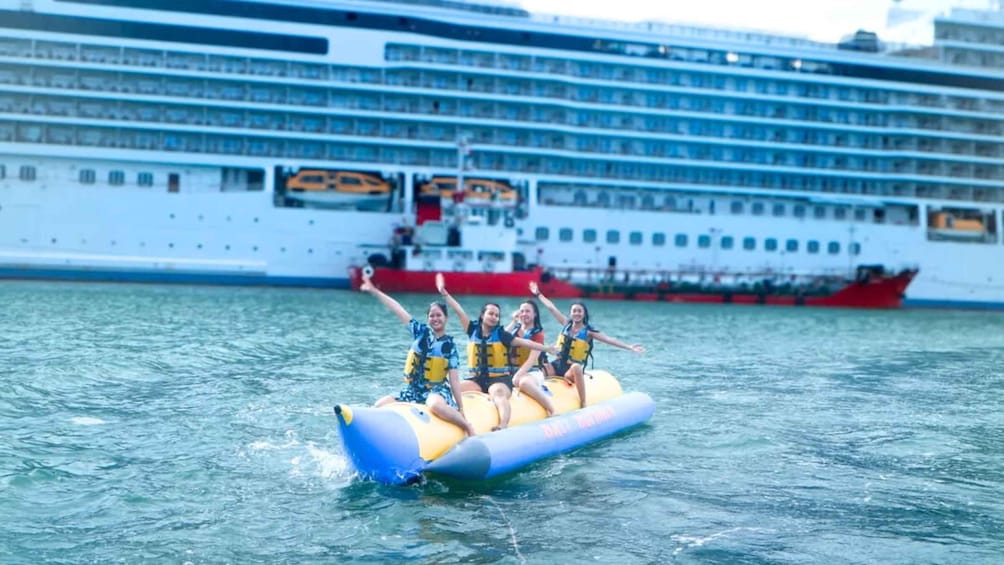 A group of people on a yellow inflatable raft in the water with a cruise ship in the background. 5