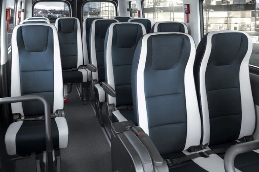 L'intérieur d'un autobus, avec des rangées de sièges, des fenêtres et une barre de maintien. 3