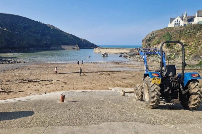 A beach with a tractor, a church on a hill, and a rocky coastline. 1