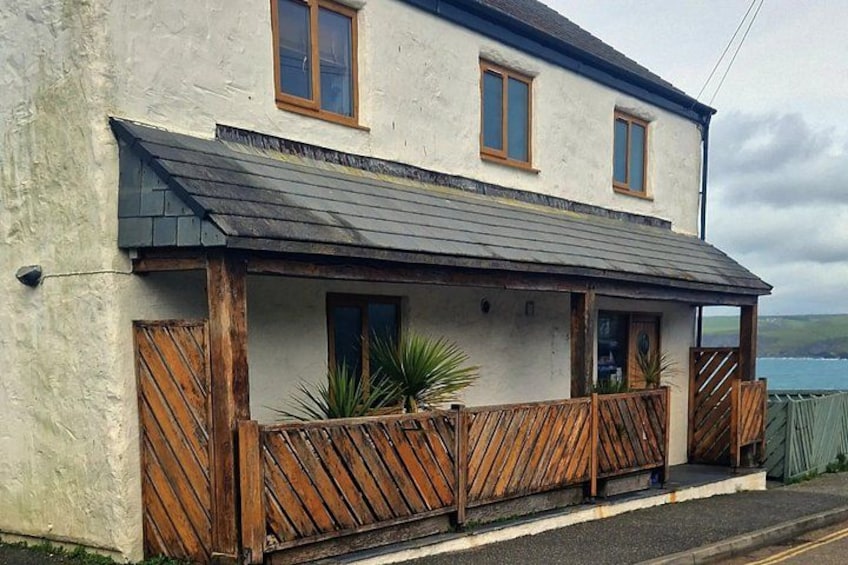 A two-story building with a balcony, wooden fence, and a view of the sea. 2