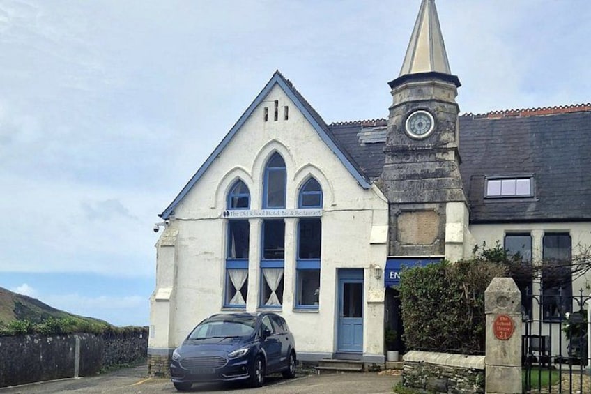A church with a clock tower, a blue door, and a parked car. 3