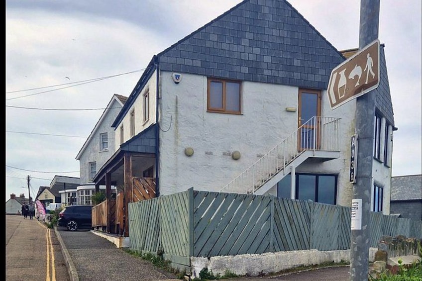 A two-story house with a grey roof, a balcony, and a pedestrian crossing sign. 4
