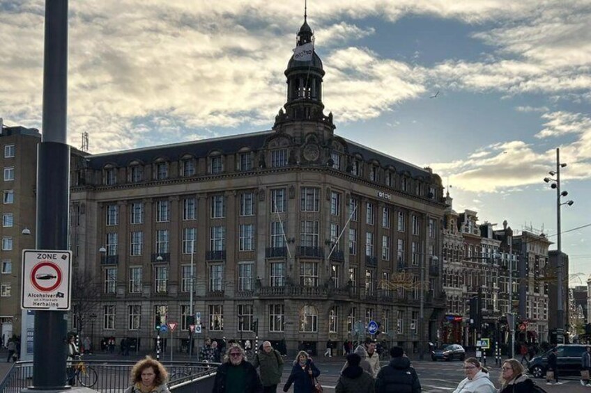 Een historisch gebouw met een klokkentoren, omringd door voetgangers en verkeersborden. 4