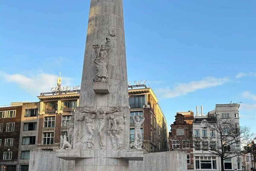 Een hoog monument met sculpturen, omgeven door gebouwen. 3