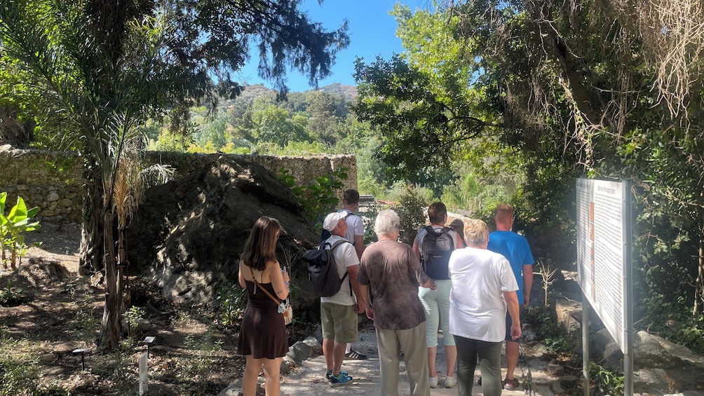 A group of people walking on a stone path surrounded by trees and a stone wall. 2