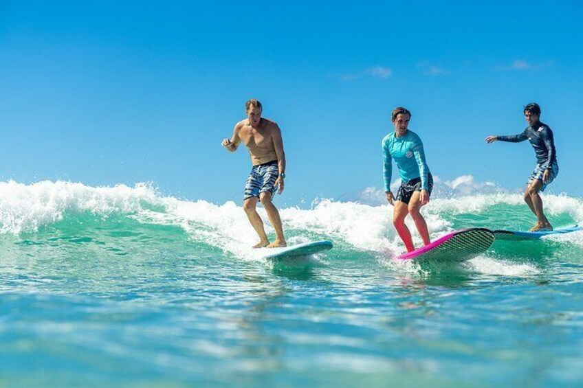 Tres personas practicando surf en un día despejado. 2