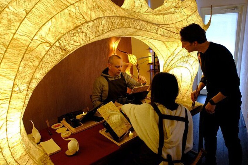 A restaurant interior with a unique paper lantern ceiling, a dining table with a red tablecloth, and a person standing by the window. 3