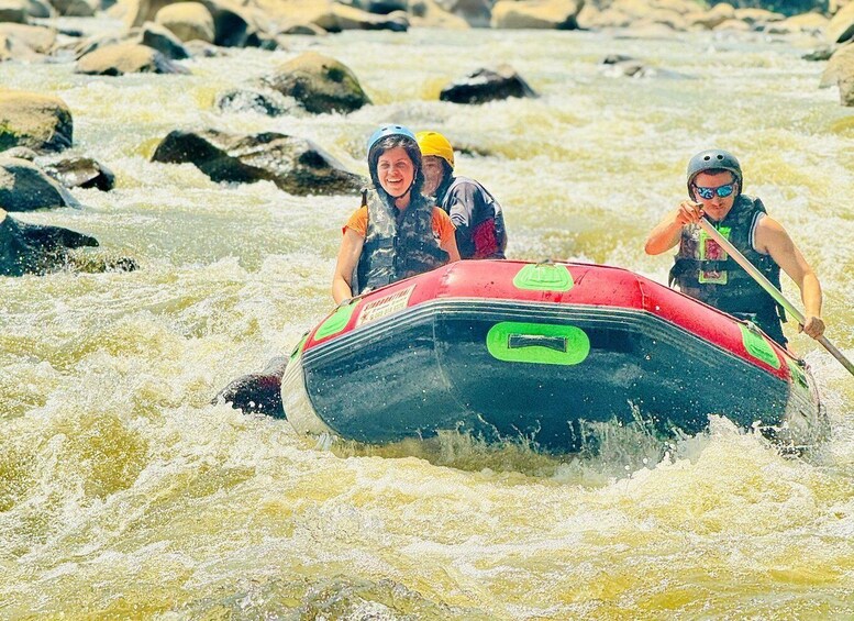 Two people in a red raft navigating through a river with white water rapids. 2