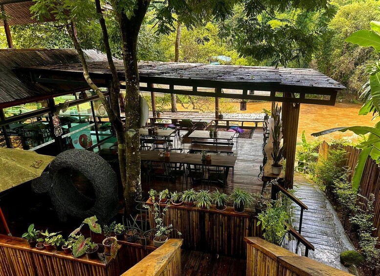A wooden deck with tables and chairs, surrounded by lush greenery and a covered seating area. 3