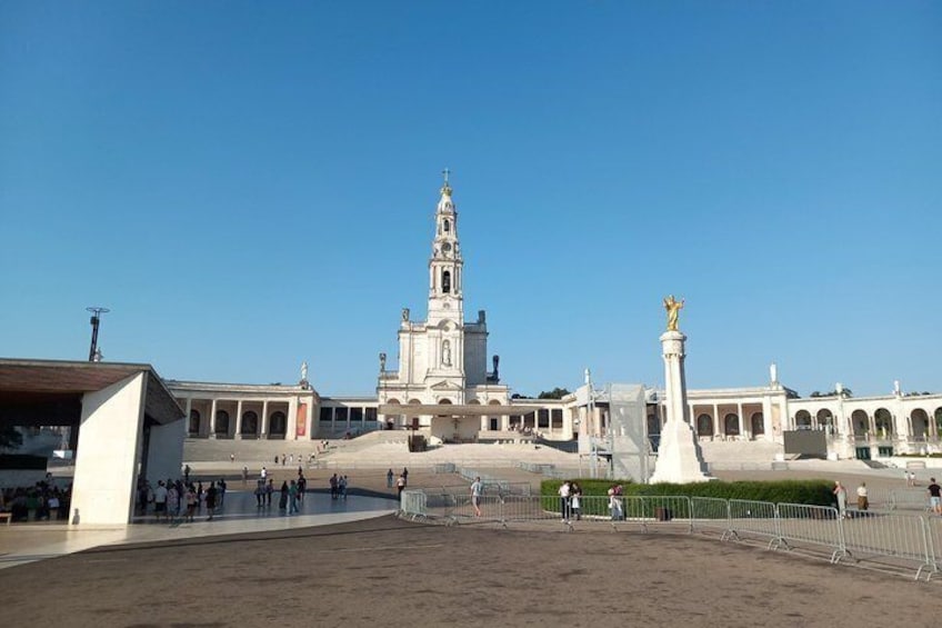 Ein großer, offener Platz mit einem markanten Kirchturm, einer Statue und einem eingezäunten Bereich. 4