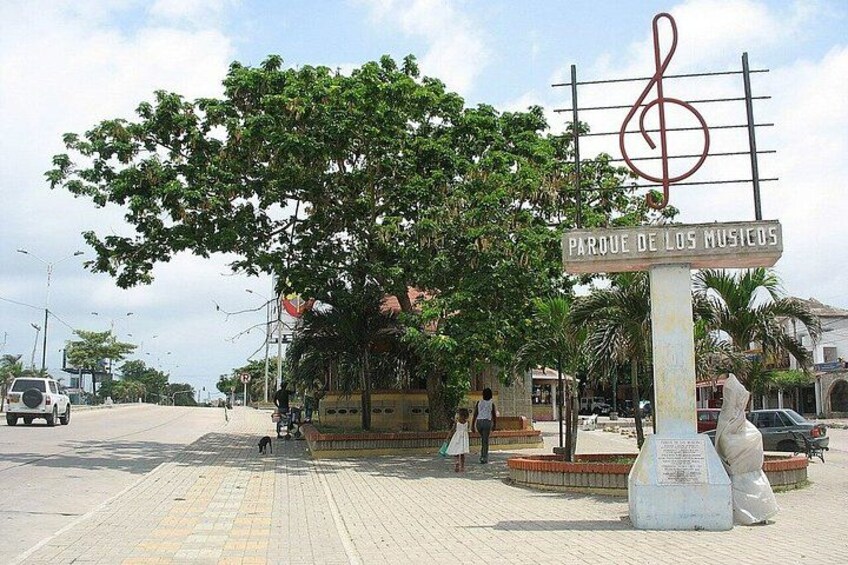 A street with a sign reading 'Parque de los Musicos,' a tree, and a statue. 3